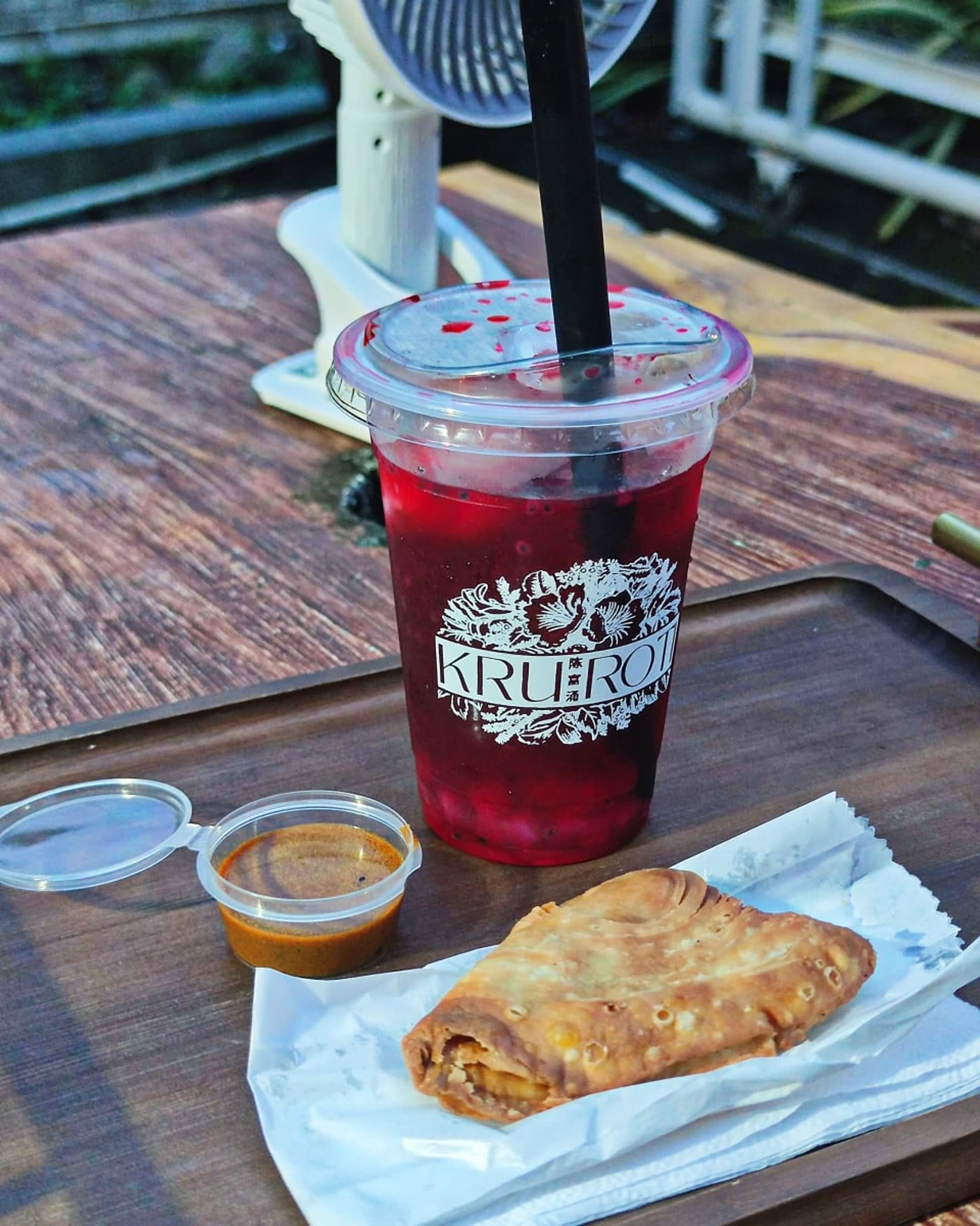 A cold bandung and a curry puff on the table outside the trailer